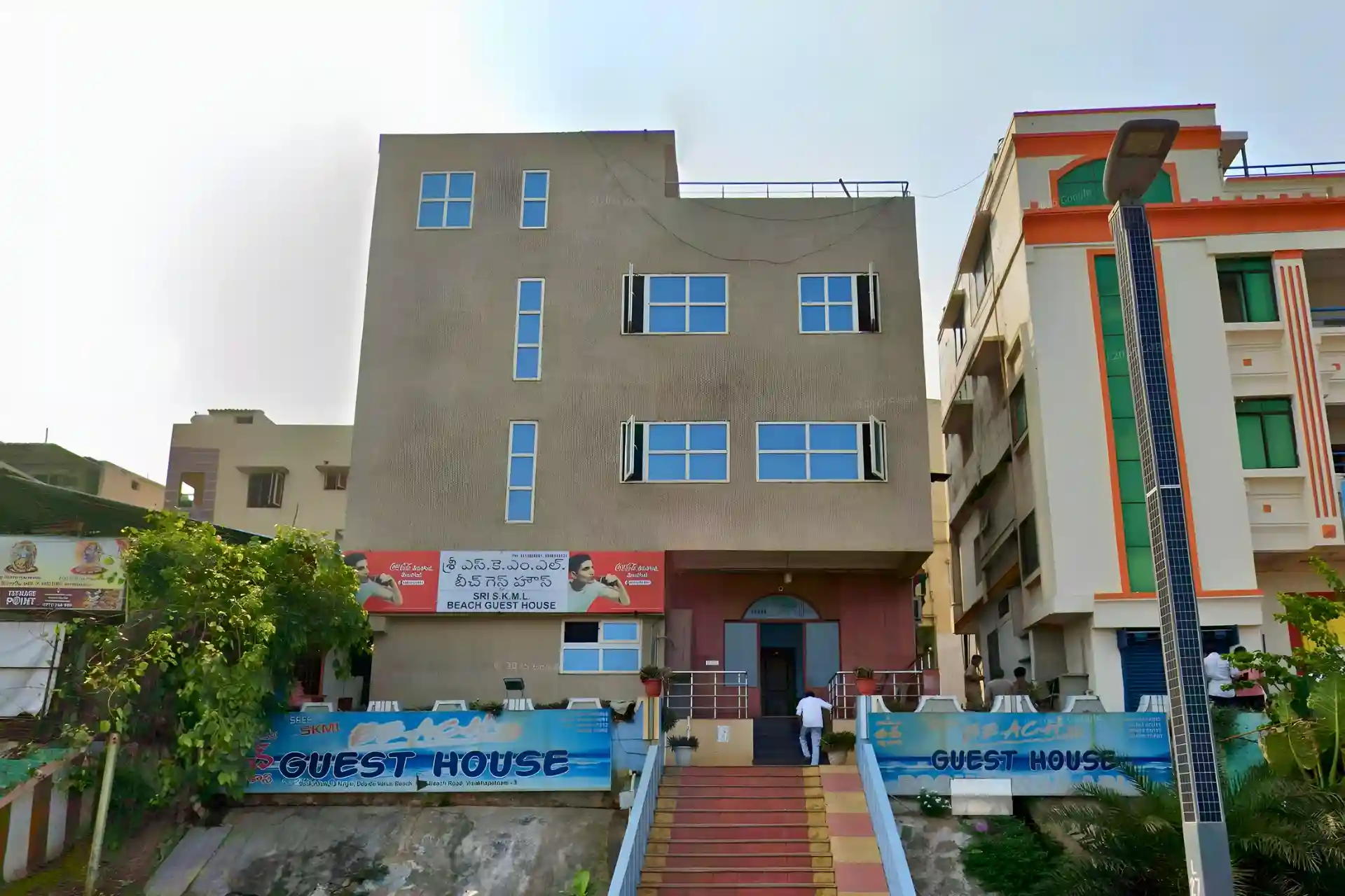 Front view of SKML Beach Guest House location and building in Vizag with roadside parking and bikes